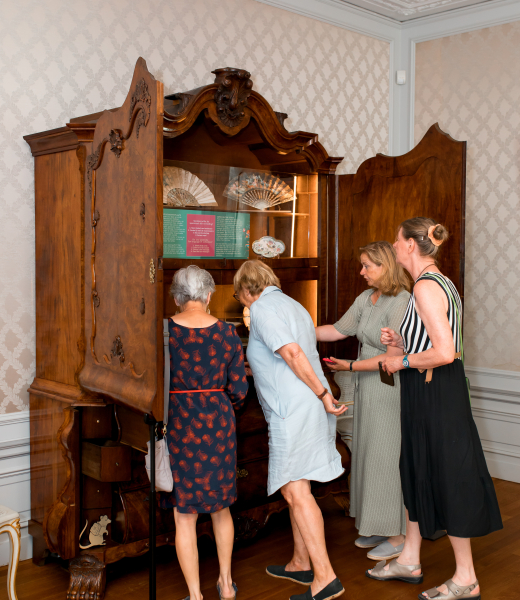 Bezoeker bekijken oude kast die tot vitrine is gemaakt. 