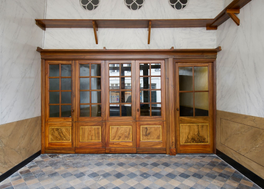 Na de restauratie zijn de historische interieurafwerkingen weer zichtbaar met het decoratieve plafond, de marmerimitaties op de wanden en de tegelvloer.