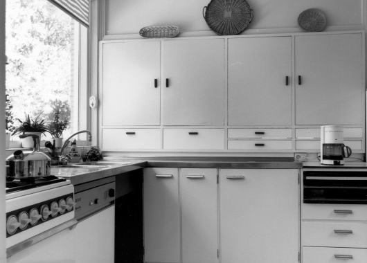 De keuken in de jaren zestig met stalen aanrechtblad, Bruynzeelkastjes en een grote doorgeefkast met warmhoudplaat.