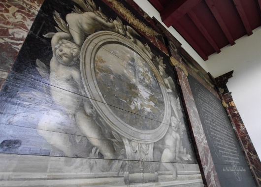 Detail van de wanddecoratie met putti, festoenen en gemarmerde onderdelen.