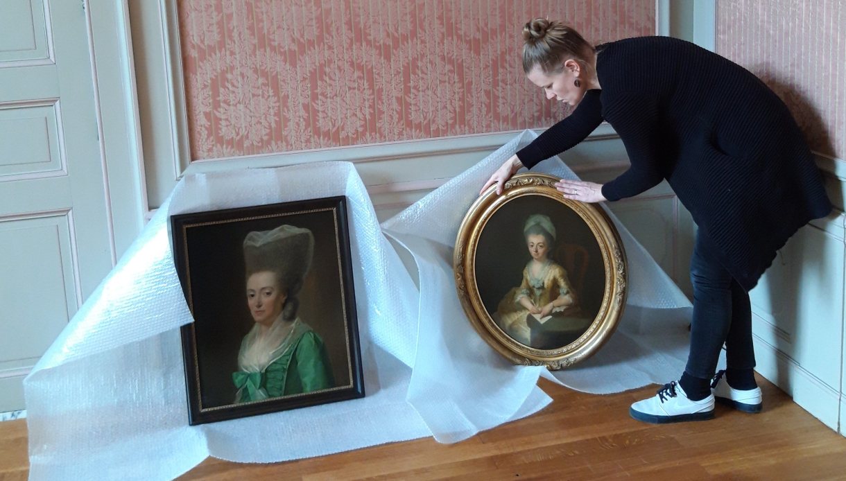 Medewerker tijdens inrichten van een museumhuis