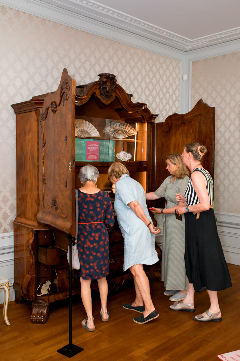 Bezoeker bekijken oude kast die tot vitrine is gemaakt. 