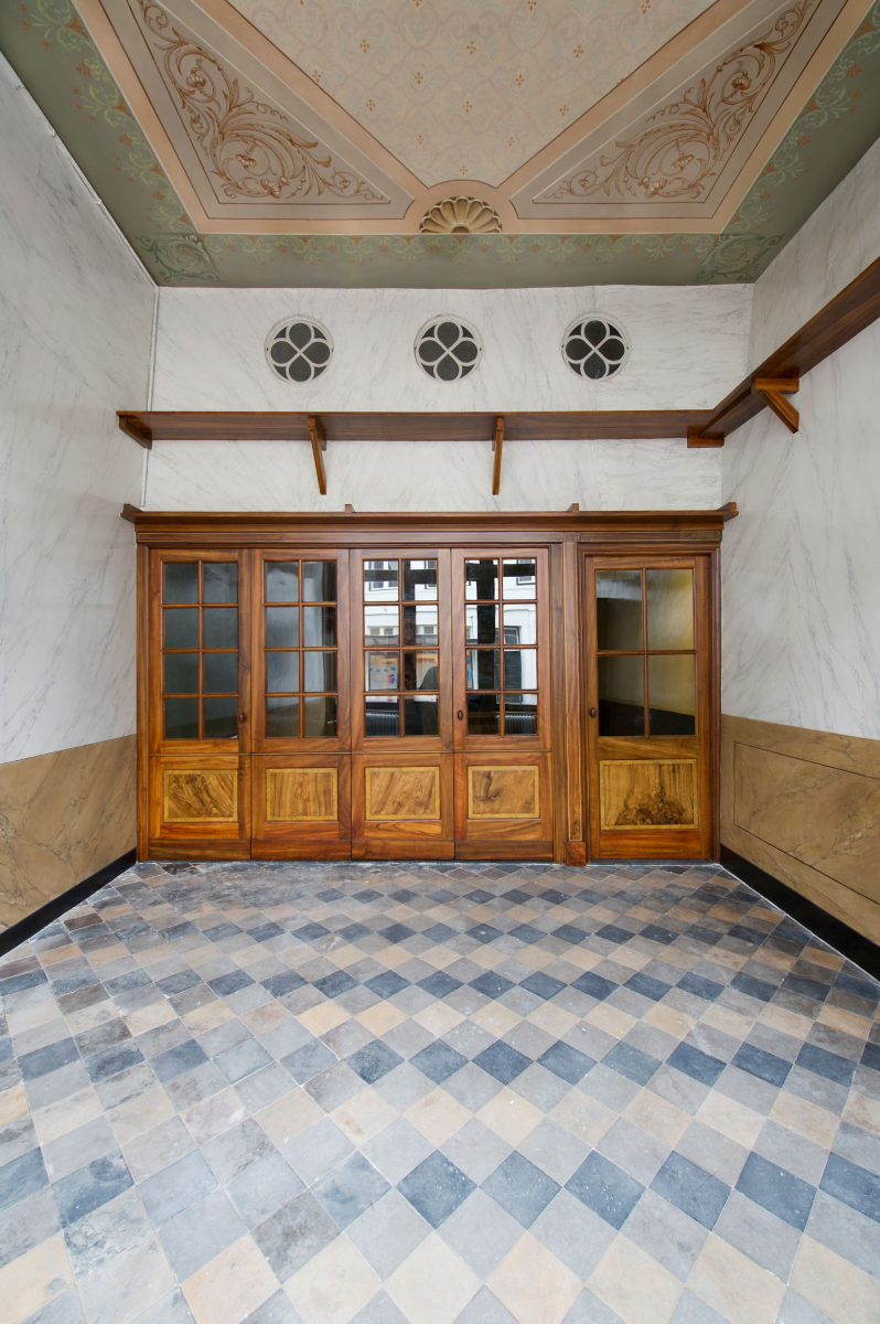 Na de restauratie zijn de historische interieurafwerkingen weer zichtbaar met het decoratieve plafond, de marmerimitaties op de wanden en de tegelvloer.