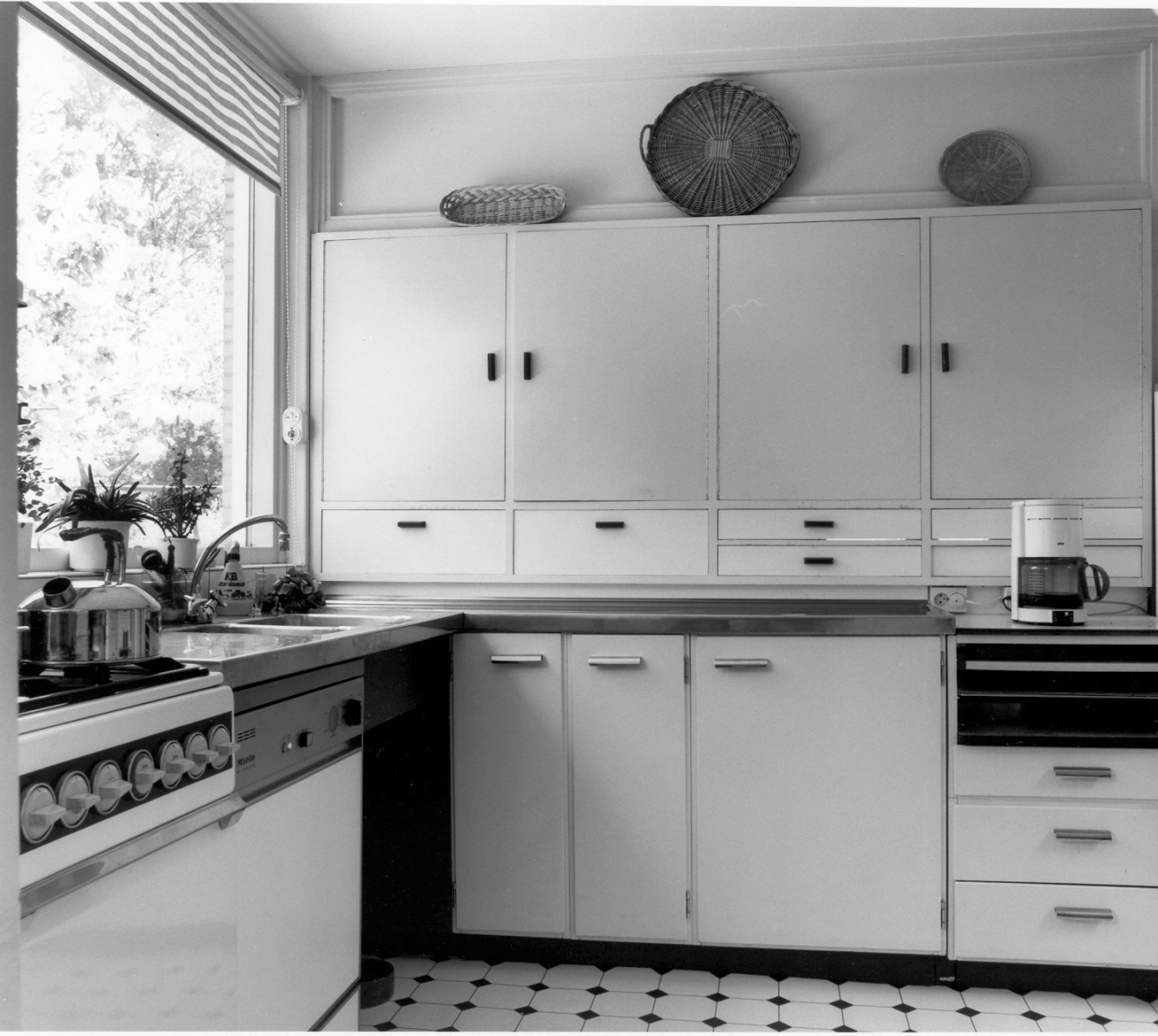 De keuken in de jaren zestig met stalen aanrechtblad, Bruynzeelkastjes en een grote doorgeefkast met warmhoudplaat.