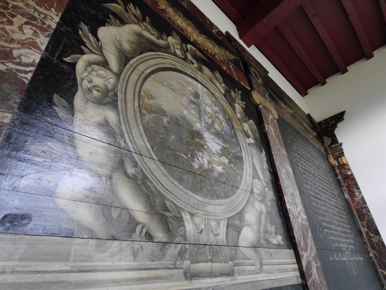 Detail van de wanddecoratie met putti, festoenen en gemarmerde onderdelen.